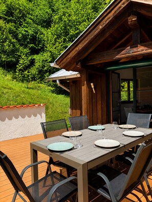 An outdoor dining area with a wooden table and chairs, surrounded by greenery. - "NaturZeit Melleck" Vacation Rental (Schneizlreuth)