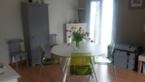 A dining area with a round table, two chairs, a cabinet, and a window with curtains. - Cozy, fully equipped room – Ideal for students or employees (Poitiers)