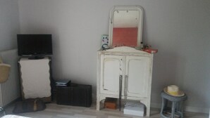 A room with a television, a cabinet with a mirror, a small stool, and a radiator. - Cozy, fully equipped room – Ideal for students or employees (Poitiers)