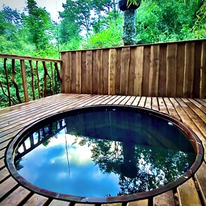 A wooden deck with a circular pool, surrounded by a wooden fence and trees. - Cabañas Huenehue (Panguipulli)