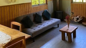 Ein gemütliches Zimmer mit Holzboden, einer Couch, einem Tisch und einem Fenster.