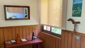 Ein Eckzimmer mit Holztisch, einem Fenster mit Jalousien, einem Spiegel und einem Poster an der Wand.