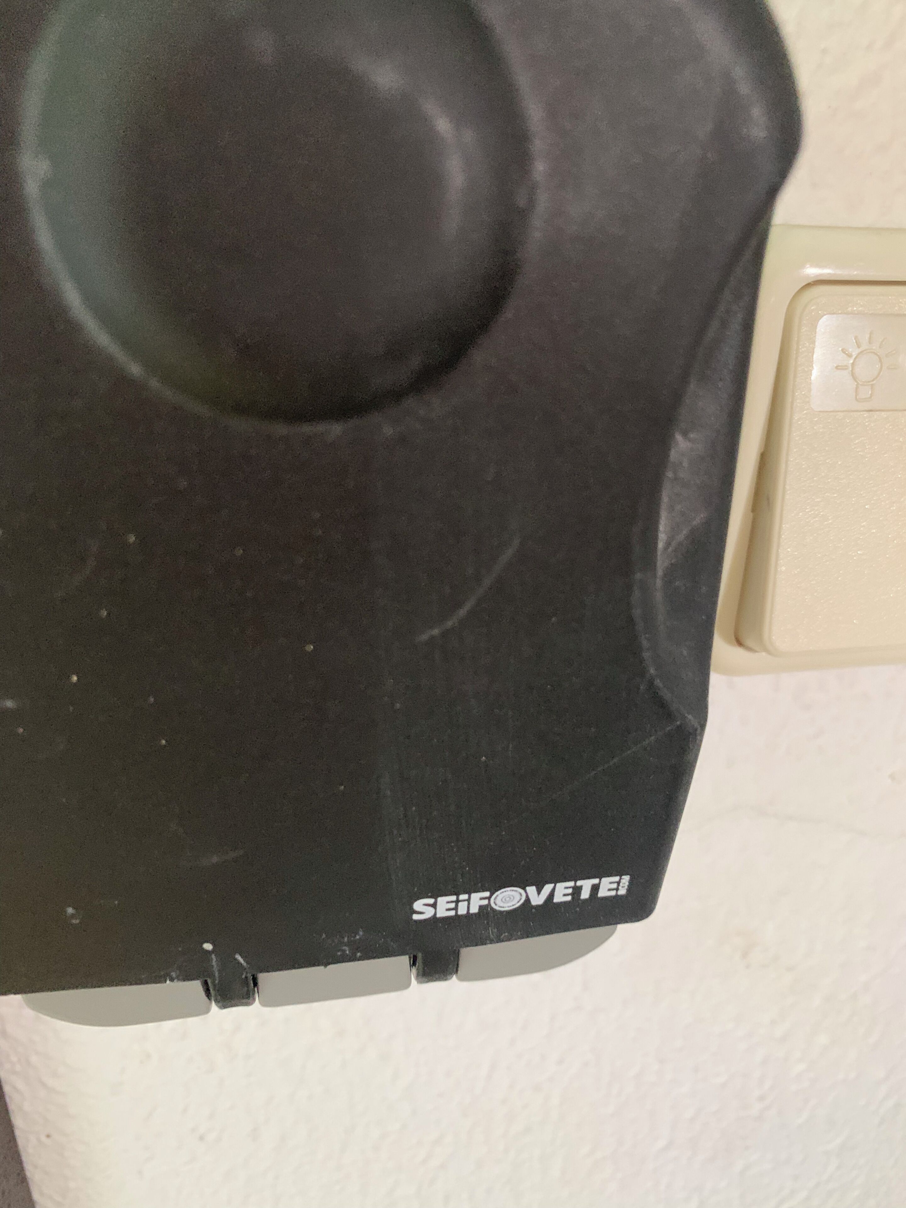 Un objeto negro con el nombre de marca 'SEIFOVETEL', posiblemente una pieza de un dispositivo o electrodoméstico.