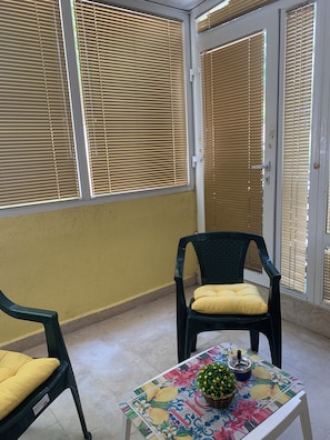 A room with two chairs, a table with a floral tablecloth, and a door with blinds. - Kabakum Beach Pool Studio Sea & Sun Escape (Varna)