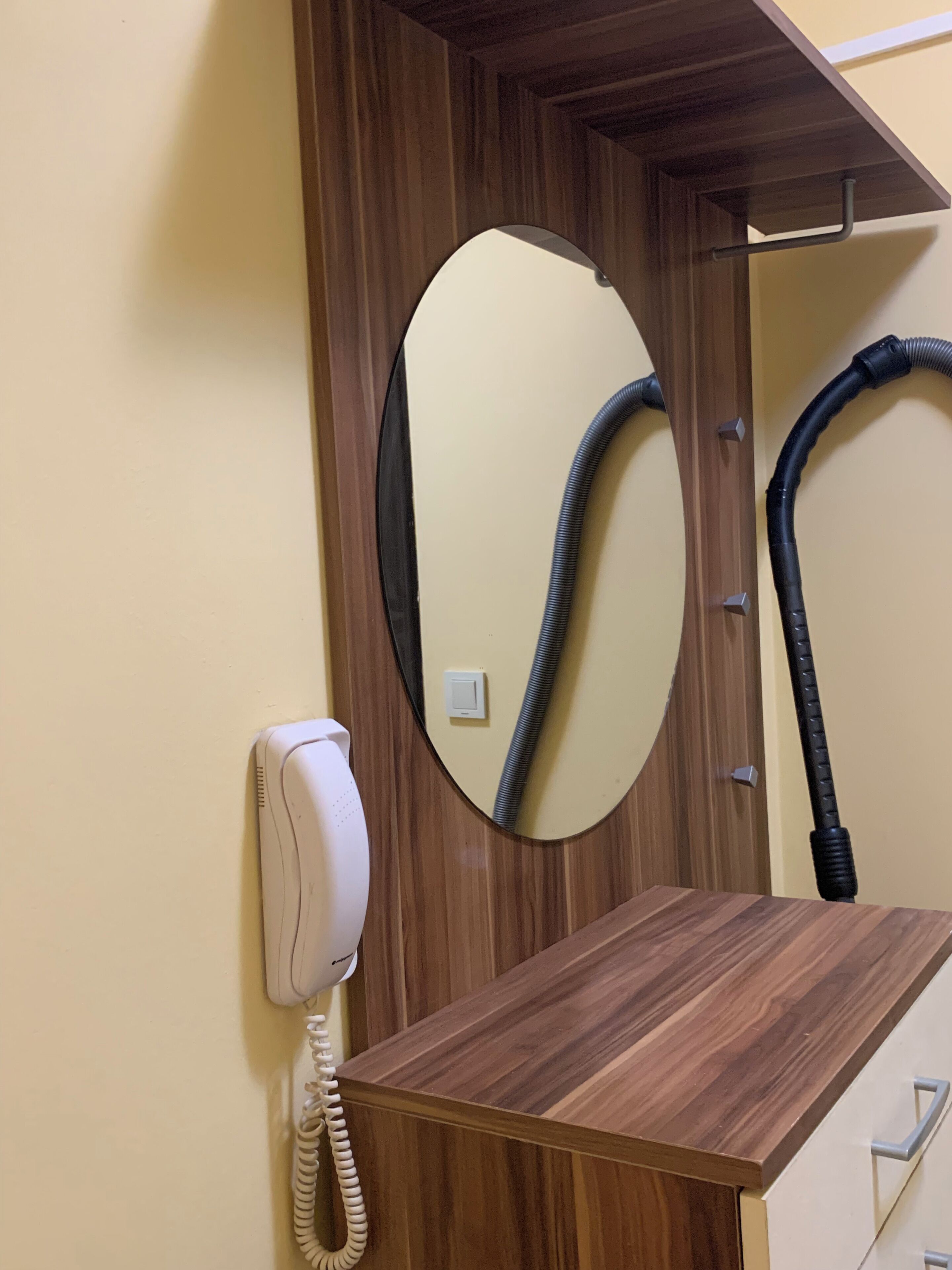 A wooden desk with a telephone and a mirror.