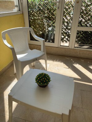 A white plastic chair and table on a balcony with a potted plant. - Kabakum Beach Pool Studio Sea & Sun Escape (Varna)