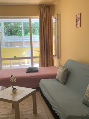 A room with a bed, a sofa, a small table with a plant, and a window with curtains. - Kabakum Beach Pool Studio Sea & Sun Escape (Varna)