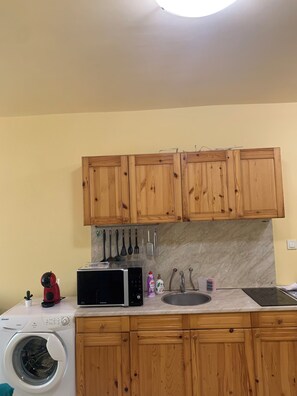 A kitchen with wooden cabinets, a washing machine, a microwave, and a sink. - Kabakum Beach Pool Studio Sea & Sun Escape (Varna)