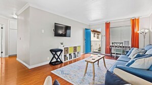 Een woonkamer met een bank, salontafel en een aan de muur bevestigde televisie.