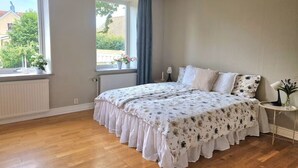 Et sovev ærelse med en stor seng, et vindue med udsigt, en radiator og et lille bord med en lampe.