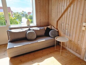 A wooden-paneled room with a sofa and a small round table. - Lovely house with a garden and pool in Österlen – Villa Harmoni (Löderup)