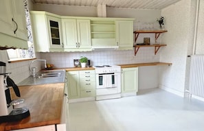 A kitchen with white cabinets, a stove, and a sink.