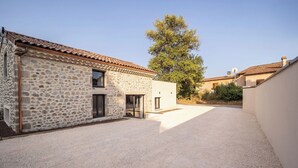 A stone building with a tiled roof, a gravel courtyard, and a tree. - The Ostalet in Sampzon  (Sampzon)