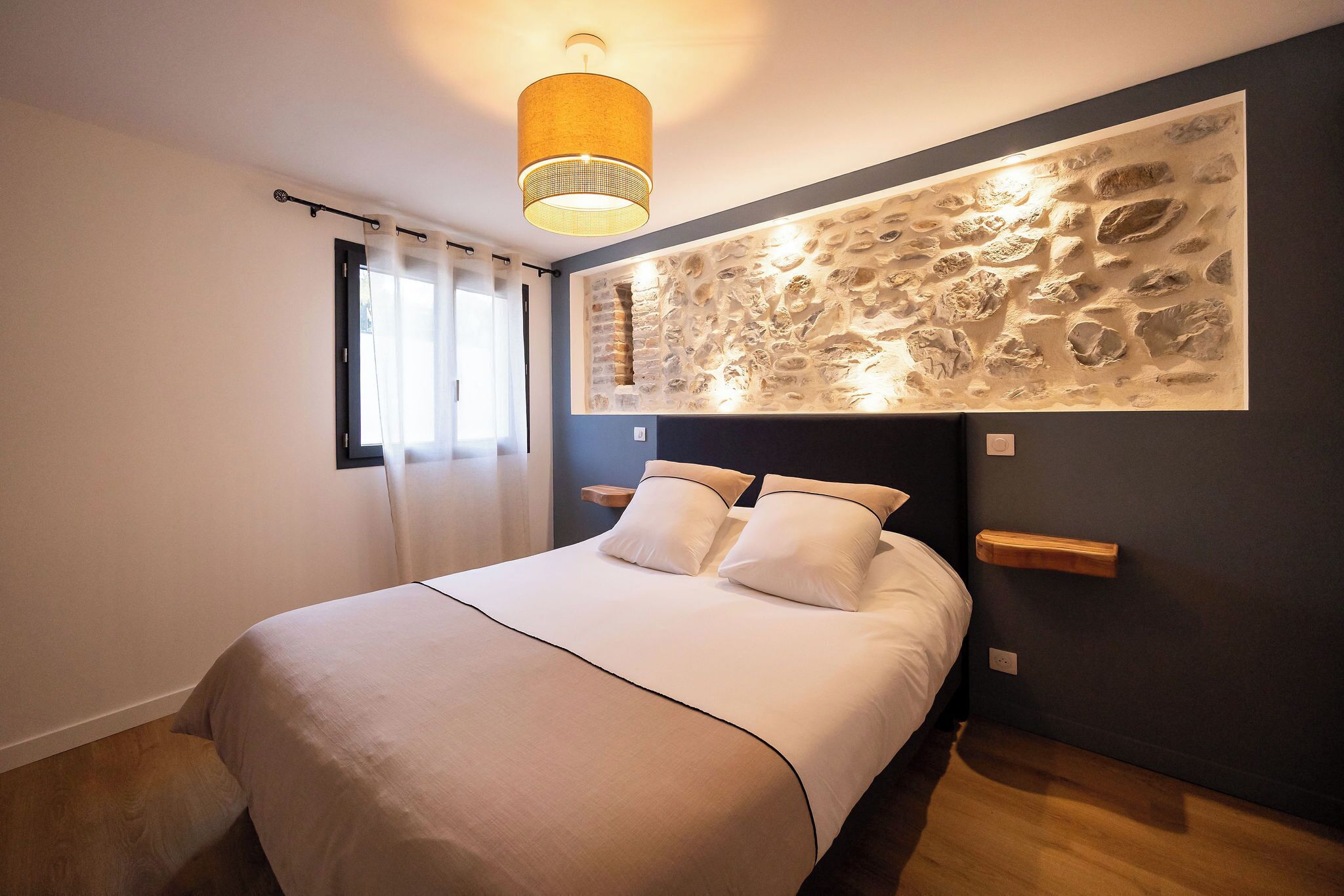 Ein Schlafzimmer mit einem Bett, einer Wandleuchte und einer Wanddekoration mit Struktur.