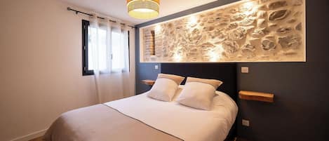 Ein Schlafzimmer mit einem Bett, einer Wandleuchte und einer Wanddekoration mit Struktur.