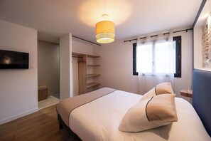 Ein Schlafzimmer mit einem Bett, einem Fernseher, einem Kleiderschrank und einem Fenster.