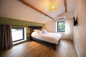 A bedroom with a bed, a window, a ceiling light, and a wall-mounted TV. - The Ostalet in Sampzon  (Sampzon)