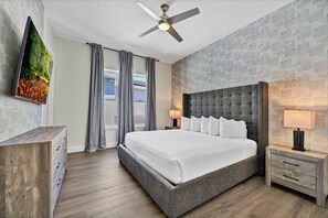 Ein modernes Hotelzimmer mit einem großen Bett, einem Deckenventilator, einem Fernseher und Blick ins Freie.