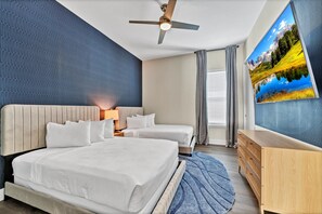 A hotel room with a large bed, two smaller beds, a wooden dresser, a ceiling fan, and a large window with curtains. - Superb Home near Disney with Resort & Waterpark Access - 960JN (Kissimmee)