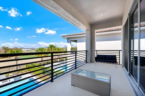 A balcony with a glass table and bench, overlooking a swimming pool and a view of the mountains. - Superb Home near Disney with Resort & Waterpark Access - 960JN (Kissimmee)