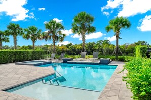A swimming pool with lounge chairs, palm trees, and a hedge. - Superb Home near Disney with Resort & Waterpark Access - 960JN (Kissimmee)