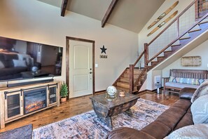 A living room with a TV, fireplace, staircase, and a star decoration on the wall. - The Firefly House at Selah Manor- BIG Lake Views on all sides of the House! (Shelby)