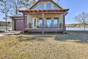 Ein Haus mit überdachter Veranda, Garage und Seeblick.