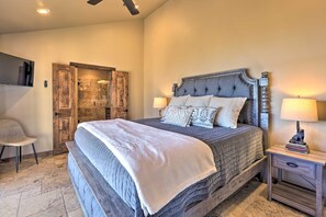 Quarto com uma cama grande, um guarda-roupa de madeira, uma cadeira e uma mesa de cabeceira com luminária.
