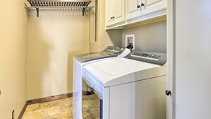 A laundry room with two stacked front-loading washers and dryers, a metal drying rack, and white cabinetry above. - The Lighthouse at Selah Manor- BIG Lake Views on all sides of the House! (Shelby)
