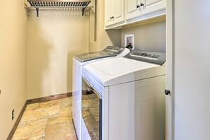 A laundry room with two stacked front-loading washers and dryers, a metal drying rack, and white cabinetry above. - The Lighthouse at Selah Manor- BIG Lake Views on all sides of the House! (Shelby)