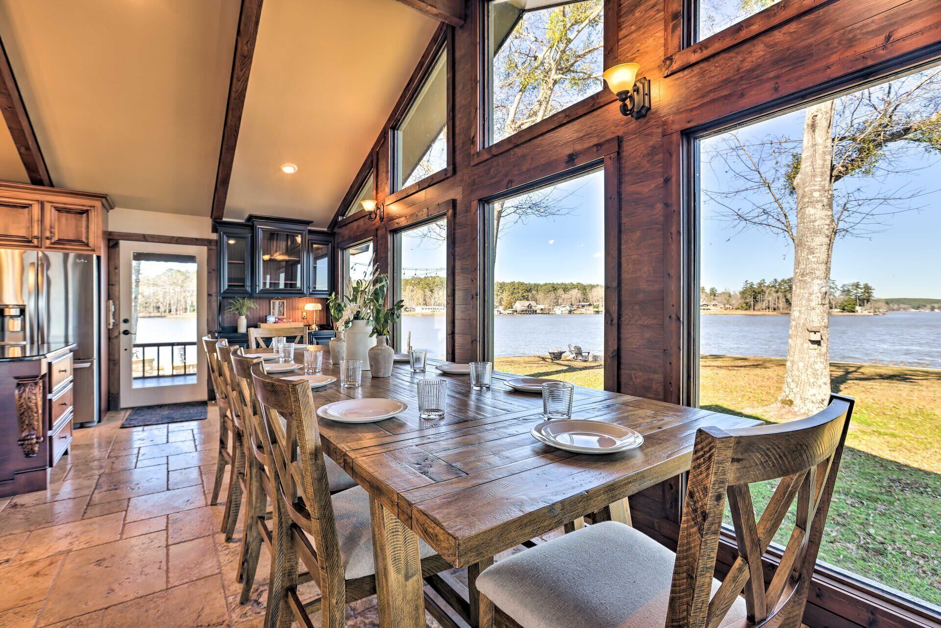 Un comedor con vistas a un lago, muebles de madera y un ventanal grande.