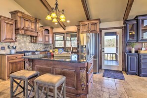 A spacious kitchen with a large island, wooden cabinetry, and a view to the outside. - The Lighthouse at Selah Manor- BIG Lake Views on all sides of the House! (Shelby)