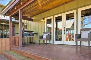 Eine überdachte Veranda mit Grill, Korbmöbeln und einer Holzterrasse.