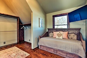 A bedroom with a bed, a window, a wooden floor, and a hanging clothes rack. - The Lighthouse at Selah Manor- BIG Lake Views on all sides of the House! (Shelby)