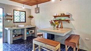 Una cocina con techo de madera, una ventana de diseño calado y una encimera con un jarrón de flores.