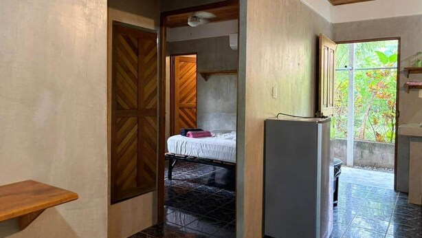 Una habitación con cama, una mesita, un refrigerador y vistas al exterior.
