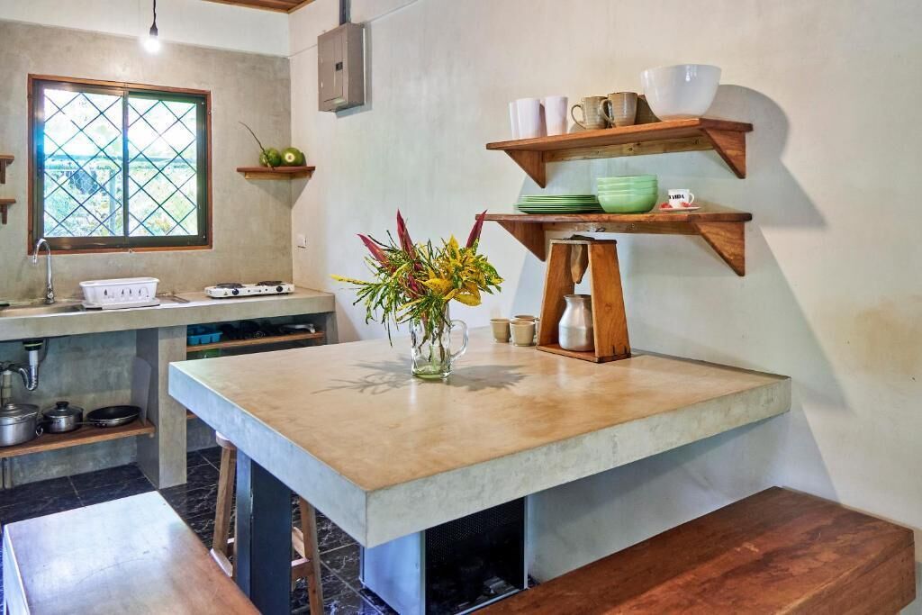 Una cocina con una isla grande, estantes de madera y un ventanal.