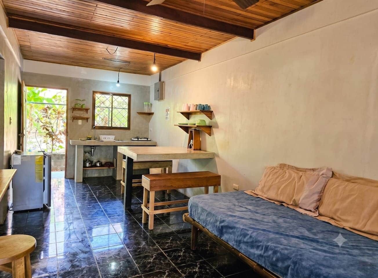 Un espacio habitable compacto con kitchenette, cama y zona de comedor.