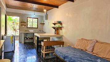 Un espacio habitable compacto con kitchenette, cama y zona de comedor.