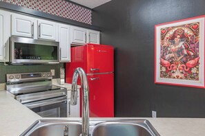 A kitchen with a red refrigerator, stainless steel appliances, white cabinets, and a decorative wall piece. - Ultra-themed family stay with Game Room minutes from Disney (Kissimmee)