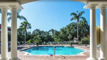 Une piscine avec des chaises longues et des palmiers en arrière-plan.