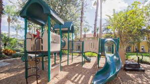 Ein Spielplatz mit Rutsche, Klettergerüsten und einem überdachten Bereich.