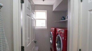 Un lavadero con una puerta que dice 'Lavandería', una lavadora y una ventana.