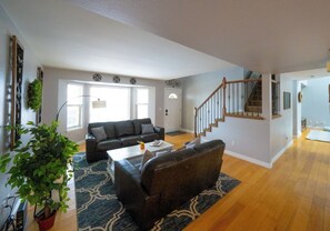 Un salón amplio con un sofá grande, una mesa de centro y una escalera que conduce a otro nivel.