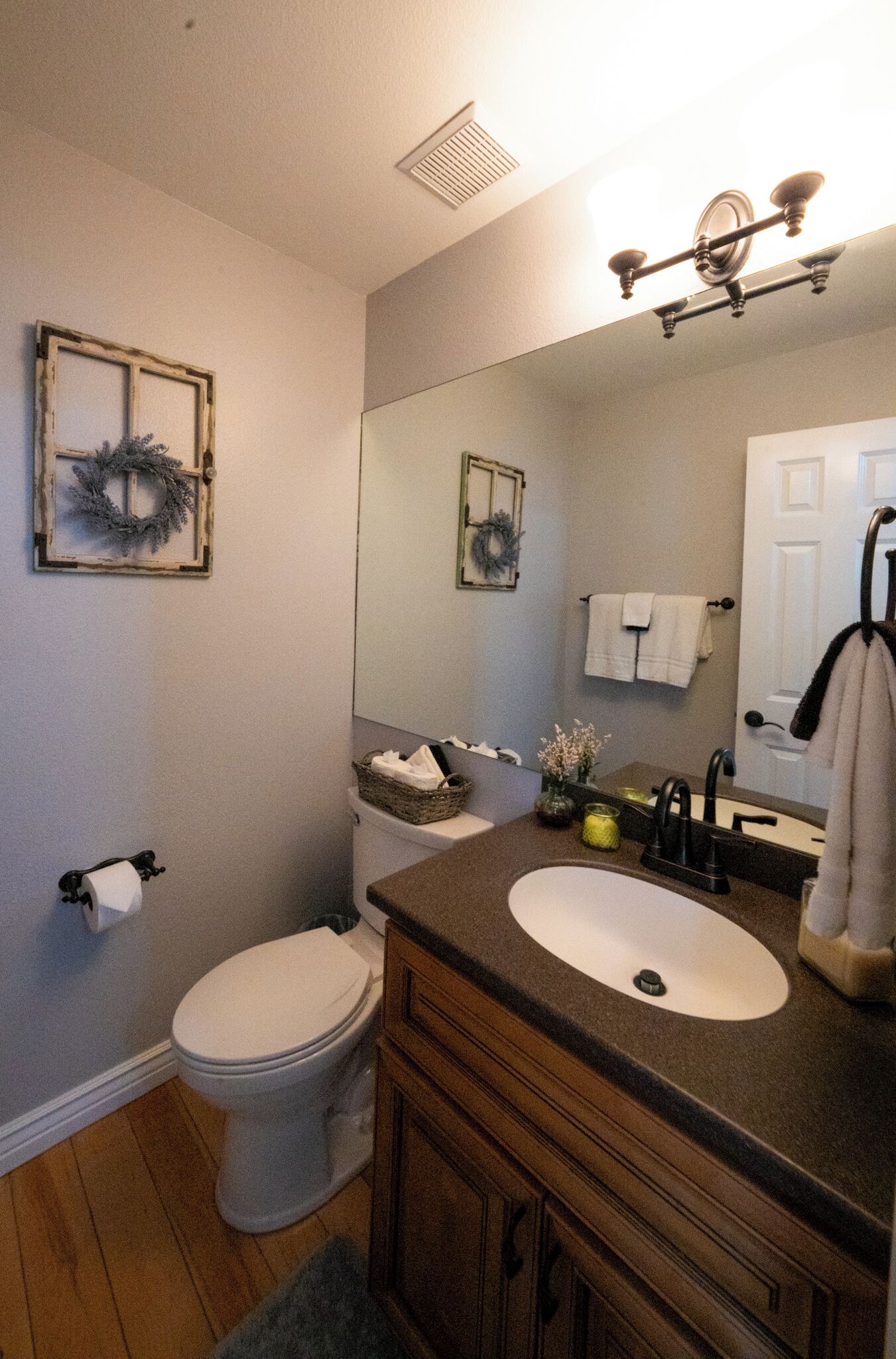 A bathroom with a toilet, sink, vanity, and a mirror.