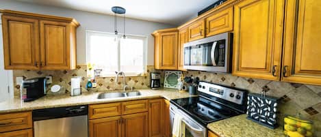 A kitchen with wooden cabinets, a microwave, a stove, a dishwasher, and a window.