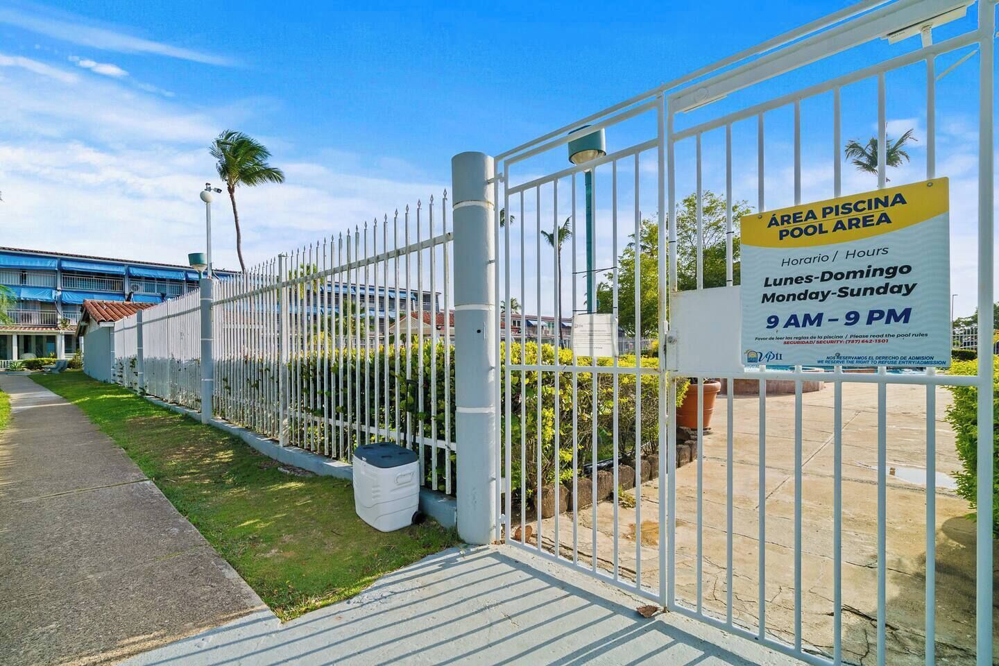 Área de piscina cercada con un cartel que indica los horarios de funcionamiento.