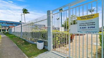 Área de piscina cercada con un cartel que indica los horarios de funcionamiento.