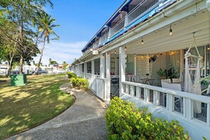 Un hôtel situé en bord de mer, doté d’un espace extérieur couvert avec des sièges, d’un chemin menant à l’entrée et offrant une vue sur l’océan.
