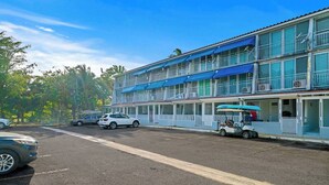 Een hotel met meerdere verdiepingen, balkons, een parkeerplaats en een golftrolley.
